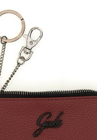 Portafoglio in pelle rossa con zip nera, dotato di una catena e di un attacco per portachiavi. Dettaglio del logo in rilievo sulla parte frontale.