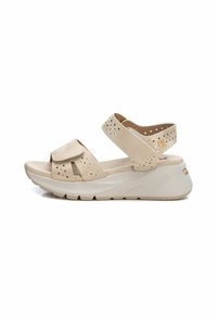 Sandalias de cuña beige con correas perforadas, banda ajustable en el tobillo y plantilla acolchada. Suela ligera con dibujo texturizado para mayor agarre.