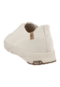 Scarpa casual bianca in maglia con superficie testurizzata, retro rinforzato, etichetta in sughero marrone e suola in gomma. Design minimalista con tocchi ecologici.