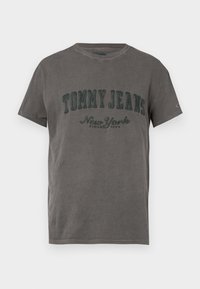 Šedé bavlněné tričko s kulatým výstřihem a krátkým rukávem. Na přední straně je vytištěno "TOMMY JEANS" a "New York" v zelené barvě.