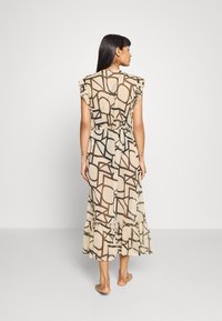 Maxi-jurk in beige met een bruin geometrisch patroon, met ruches op de mouwen en een gelaagde zoom. Lichtgewicht, vloeiende stof.