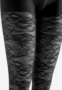 Svarta leggings med ett blommönstrat spetsmönster i den övre delen, med en texturerad meshdesign, tillverkade av ett stretchy material.