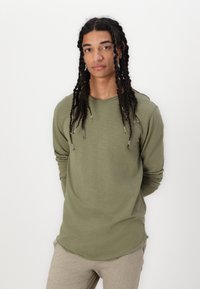 Olivenfarbener Langarm-T-Shirt aus weichem Material, mit rundem Ausschnitt, leicht geschwungenem Saum und überschnittenen Schultern.