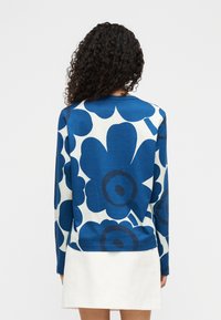 Μπλε και λευκό πουλόβερ με λουλουδένιο μοτίβο, μακριά μανίκια, στρογγυλή λαιμόκοψη και άνετη εφαρμογή, με μεγάλα σκούρα μπλε λουλούδια σε ανοιχτό φόντο.