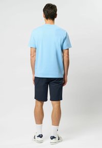 Light blue cotton t-shirt, short sleeves, crew neck, paired with navy shorts, white socks, and white sneakers with navy accents.