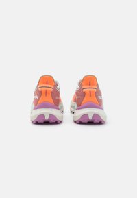 Trailrunning schoenen met een meerkleurig ademend mesh bovenwerk, oranje accenten, een dikke witte tussenzool en een textuur rijke paarse buitenzool.