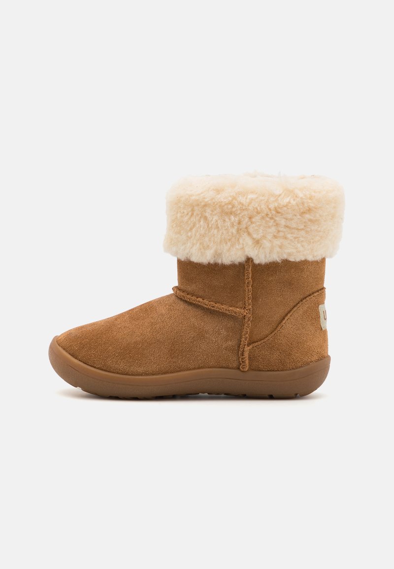 Bottines en cuir suédé marron avec un col en fausse fourrure crème pelucheux, bout arrondi et semelle en caoutchouc. Détails de couture sur le côté et logo de la marque à l'arrière.