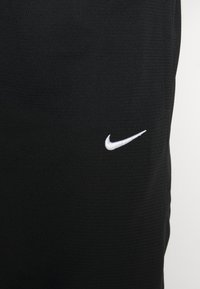 Pantalones cortos atléticos negros con una tela texturizada, con un pequeño logo de Nike en blanco en el lado izquierdo.