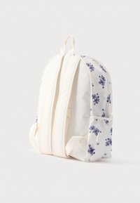 Λευκό υφασμάτινο σακίδιο πλάτης με μοτίβο μωβ λουλουδιών, επενδυμένη πλάτη, διπλό φερμουάρ και πλαϊνή τσέπη για επιπλέον αποθήκευση.