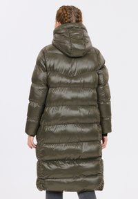 Olivgrön pufferjacka med huva, med en quiltad design, glänsande textur och lång längd som når mitt på vadbenet.