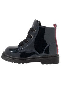 Černé lakované kozačky nad kotníky s lesklým povrchem, kulatou špičkou, černými šněrováním a červeným akcentem na podpatku. Gumová podrážka s vzorkem.