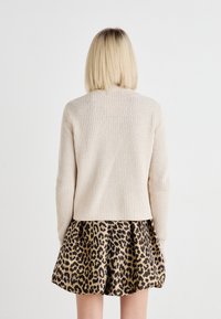 Beige stripete genser med lange ermer, kombinert med et brunt og svart leopardmønstret skjørt med en utstående, plisserte design.