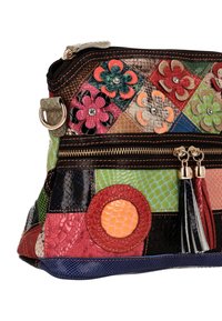 Patchwork-håndtaske lavet af teksturerede materialer i levende farver, med blomsterdetaljer, lynlås og dekorative kvaster.