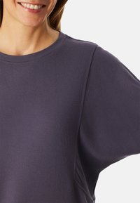 Lila Sweatshirt mit rundem Ausschnitt, weicher Textur und überschnittenen Schulternähten. Verfügt über ein minimalistisches Design ohne sichtbare Muster oder Logos.