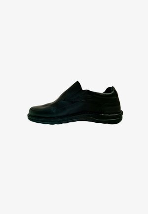 Zapatos de cuero negro de tipo slip-on con punta redonda, paneles laterales elásticos y suela de goma texturizada. Detalle de costura a lo largo de los bordes.