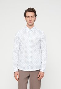 Λευκό πουκάμισο με μακριά μανίκια και ανοιχτό μπλε λουλουδάτο σχέδιο, γιακά με κουμπιά και καμπυλωτή άκρη. Κατασκευασμένο από ελαφρύ ύφασμα.