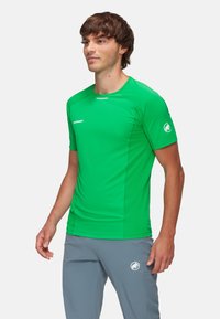 Groene sportieve shirt met korte mouwen, voorzien van een ronde halslijn, een slim-fit ontwerp en een logo op de rechtermouw. Glad, lichtgewicht materiaal.