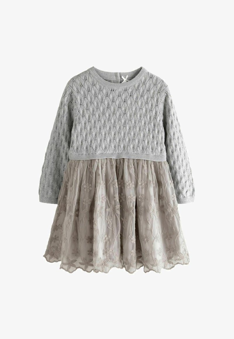 Grijze gebreide top met ruitpatroon, lange mouwen; beige tule rok met geborduurd bloemenontwerp. Elastische taille, ronde halslijn.