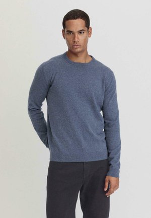 Pull en tricot bleu avec un col rond, des manches longues, et des bords-côtes aux poignets et à l'ourlet. Texture douce avec un motif chiné subtil.