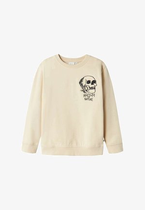 Sweatshirt beige en tissu doux, ornée d'un graphique de tête de mort noire et du texte "RYTHME DE LA NATURE" sur le côté gauche de la poitrine. Encolure ronde et poignets côtelés.