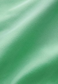 Simává, zöld szövet, amelynek enyhe fénye van, könnyű, puha textúrával és finom szövési mintával, ami folyékony megjelenést kölcsönöz.