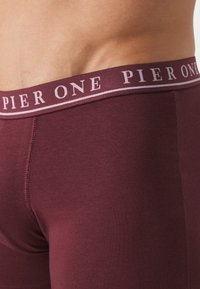 Burgunderfarbene Herrenunterwäsche mit weicher Textur, ausgestattet mit einem kontrastierenden Bund und dem "PIER ONE"-Logo in Hellrosa.