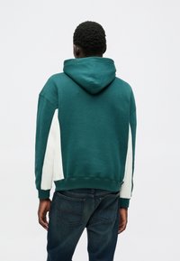 Turkusowa hoodie z białą boczną wstawką, z kieszenią kangurką i kapturem ze sznurkiem. Wykonana z miękkiego materiału, z ściągaczami przy mankietach.