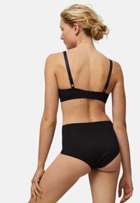 Conjunto de lencería negra que incluye un sujetador negro con tirantes ajustables y cierre de gancho, combinado con braguitas negras de talle alto. Textura suave.