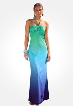Vrouw draagt een strapless avondjurk met een kleurverloop van groen naar blauw, gecombineerd met grote oorbellen en brede armbanden.