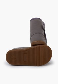 Stivale alla caviglia in pelle grigia con punta arrotondata, superficie testurizzata, suola in gomma marrone a contrasto e chiusura con strap in velcro laterale.