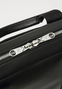 Schwarze strukturierte Lederhandtasche mit silbernem Reißverschluss und Zuglaschen. Verfügt über ein elegantes Design, einen oberen Griff und kontrastierende Nähte.
