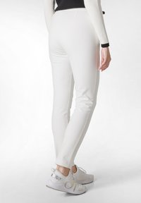 Witte aansluitende broek met een gladde textuur, voorzien van een medium hoge taille en een slanke silhouet, gecombineerd met lichte sportschoenen.