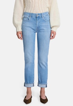 Lichtblauwe denim jeans met een slim fit, opgerolde pijpen, vijf zakken en een subtiele vervaagde textuur. Gecombineerd met een crèmekleurige gebreide trui.