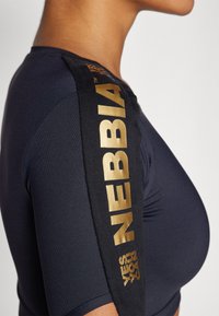 Vesipaidat navy-värissä, jossa on säädetty muotoilu, lyhyet hihat ja mustat kangasreunukset, joissa on kultaiset "NEBBIA" ja "YES YOU CAN" -tekstit.