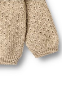 Détail d'un pull en tricot beige avec un motif texturé, des poignets et un ourlet côtelés. Fabriqué en fil doux, mettant en valeur un design ajouré complexe.