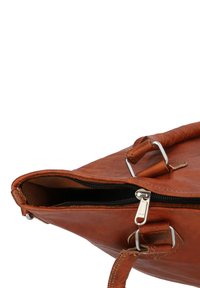 Ruda odinė rankinė su užtrauktuku, metaliniais sidabriniais aksesuarais ir tekstūriniu paviršiumi. Turi vieną rankeną ir matomą siuvinėjimą.