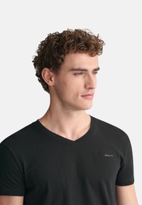 Mustat V-paitat, jotka on valmistettu puuvillasta, slim fit -mallia ja pieni brodattu logo rinnassa. Sileä pinta, rento muotoilu.