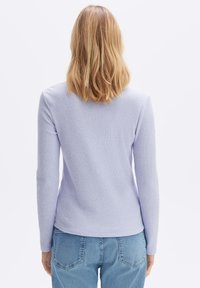 Ljuslila ribbad långärmad topp med rundad halsringning, som är matchad med ljusblå denimjeans, med bakseams och en subtil textur.