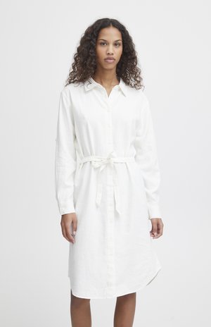 Robe blanche à boutons, en tissu léger, avec des manches longues, une taille à nouer et un ourlet mi-genoux avec un bas légèrement arrondi.