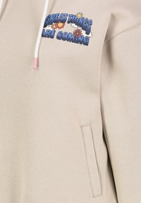 Beige hoodie met een voorzak, voorzien van een multicolor grafisch ontwerp met de tekst "GROTE DINGEN KOMEN ERAAN." Katoenmengsel.