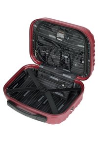 Röd hård-skal resväska med svart inredning, som har elastiska remmar, zippered fack och ett märkesfoder med flygplansmotiv.