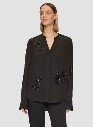 Blouse noire à manches longues avec un décolleté en V, ornée de sequins floraux noirs brillants sur le devant et les manches. Texture lisse.
