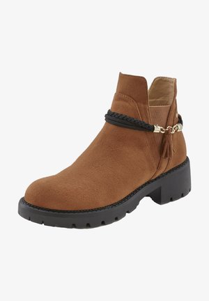 Pruunist seemisnahast pahkluu saapad, millel on massiivne must tall, kaunistatud musta palmikuga rihmaga ja dekoratiivsete tutiga detailiga.