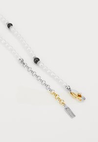 Cadena de plata y oro con perlas blancas y cuentas negras. Incluye un cierre de langosta y una pequeña etiqueta con texto.