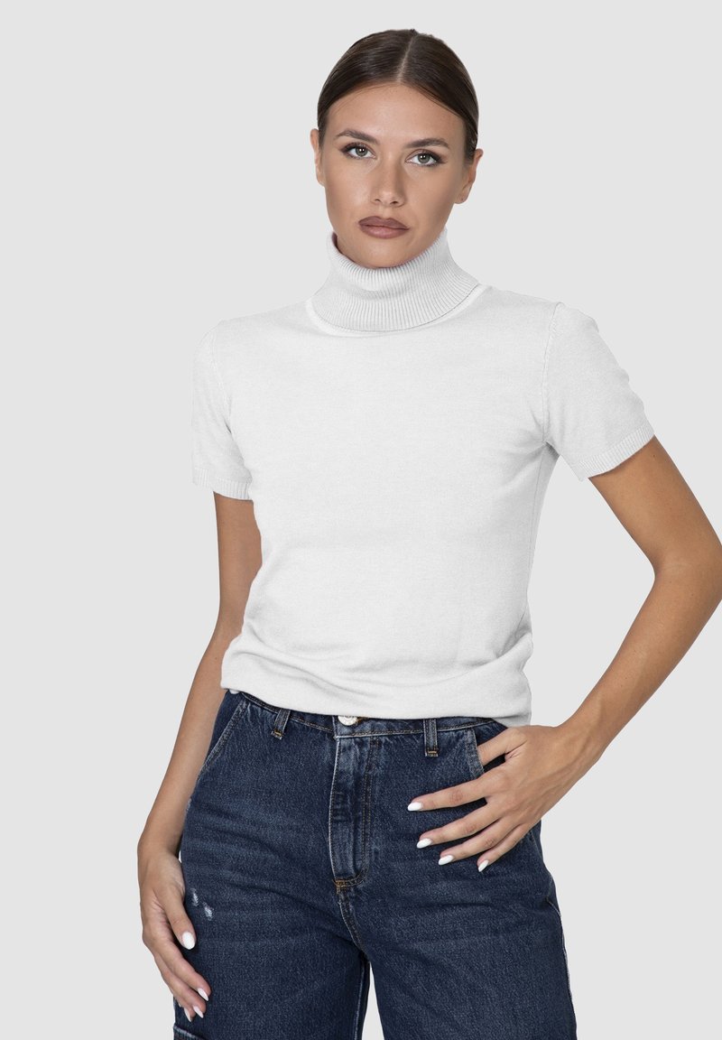 Maglione bianco a maniche corte con collo alto in materiale lavorato a maglia, con un design aderente e collo a coste, abbinato a jeans scuri a vita alta.
