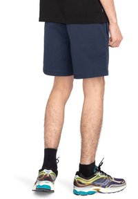 Marinblå shorts med rak passform, tillverkade av slitstark tyg. Designen har en enkel midja och sidfickor, parat med sportskor.