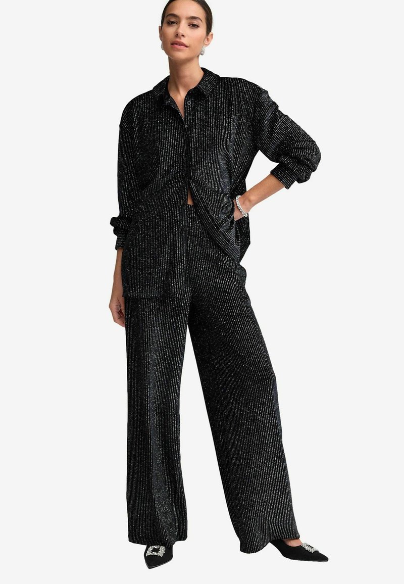 Completo due pezzi nero e scintillante composto da una camicia a maniche lunghe con bottoni in vestibilità comoda e pantaloni larghi con righe verticali e una sottile texture.
