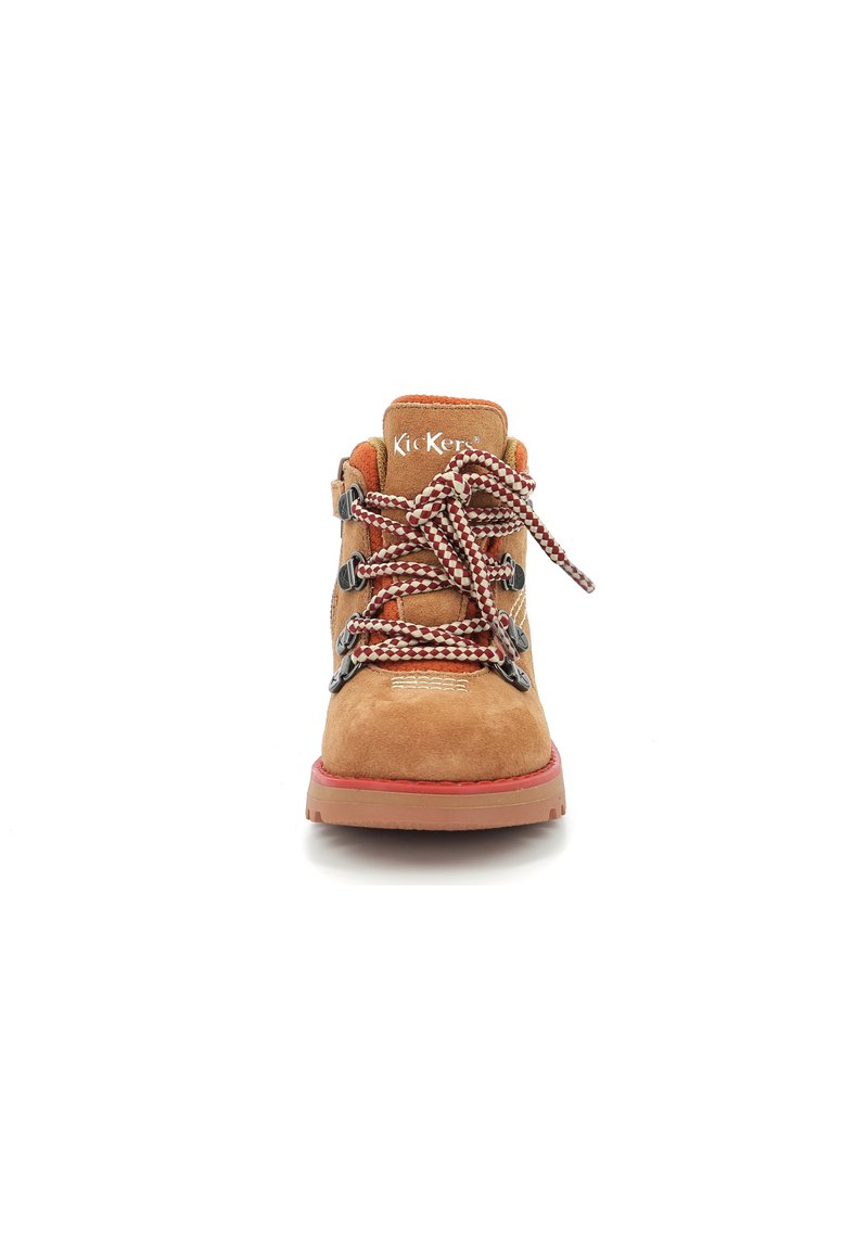 Beige Wildlederschuh für Wanderungen mit schwarzer Hardware, roten Akzenten und braunen Schnürsenkeln. Abgerundete Zehenpartie und gepolsterte Sohle für Komfort. Rote genoppte Außensohle.