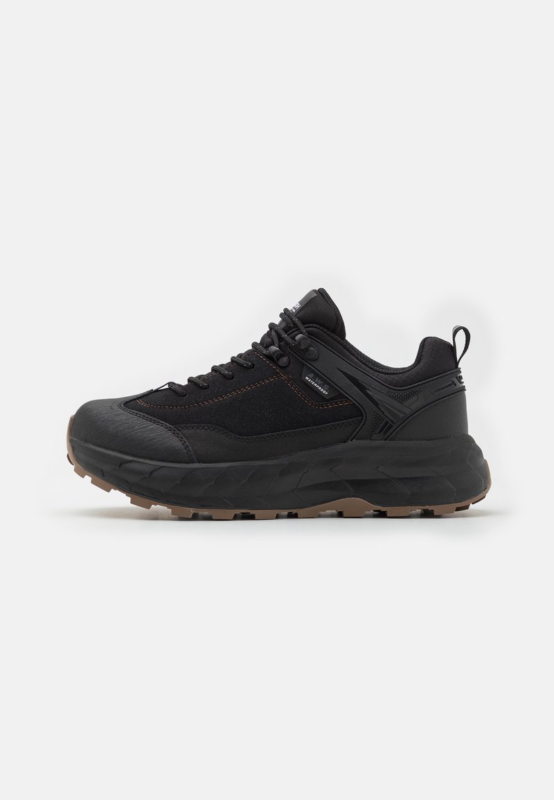 Black athletic shoes with a textured upper, reinforced toe, and a thick, rugged outsole. Features lacing system and a padded collar.