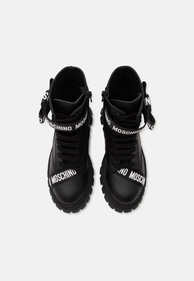 Ζευγάρι μαύρα combat μποτάκια Moschino με χοντρές σόλες, κορδόνια και λουριά με λογότυπο πάνω από τα δάχτυλα και τους αστραγάλους.